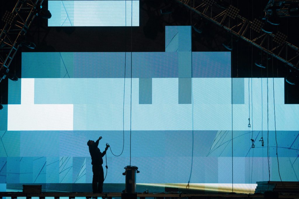 A stage technician working with equipment on a large digital screen installation.